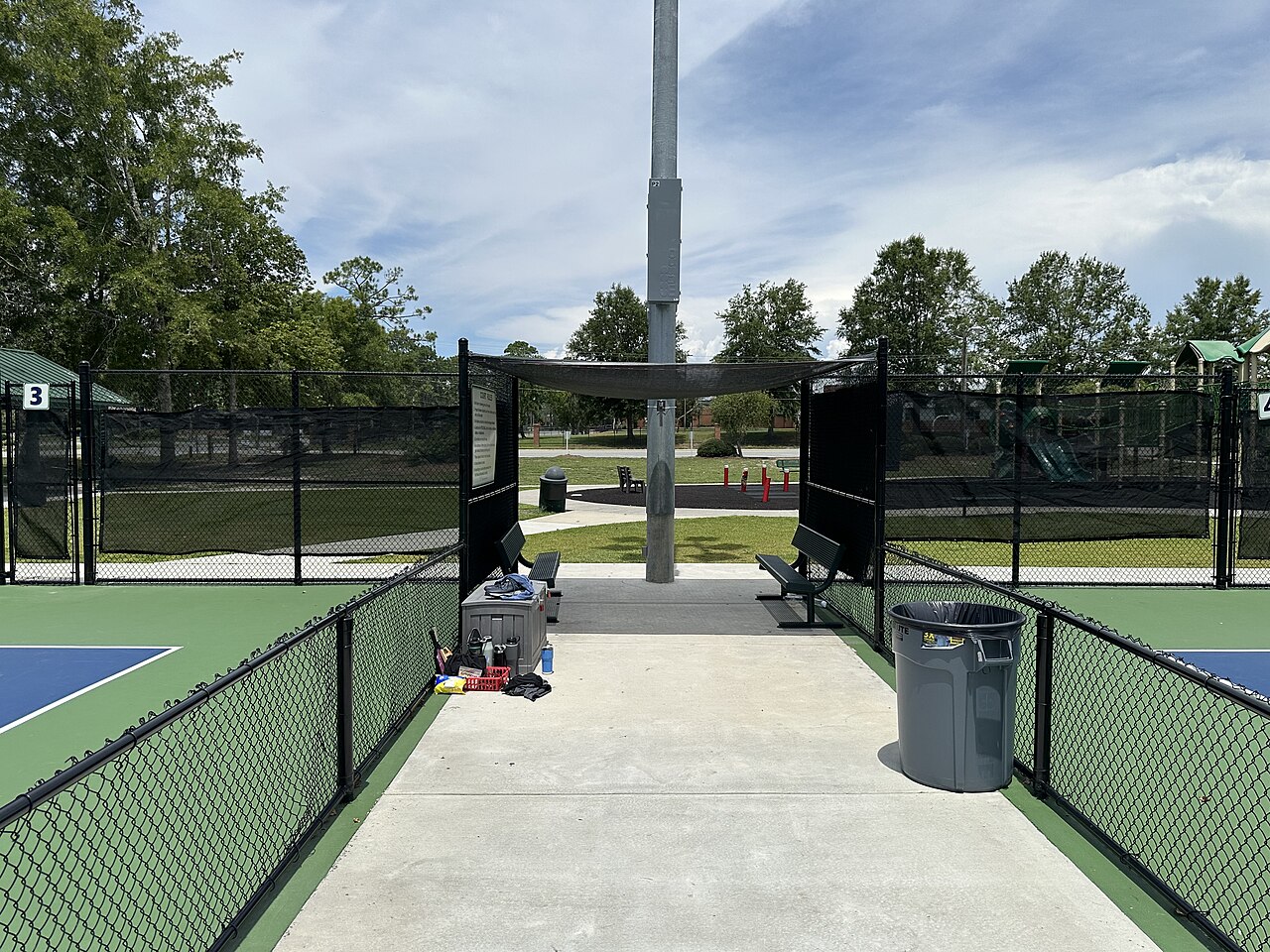 The gate into a row of fenced pickleball courts, with benches either side