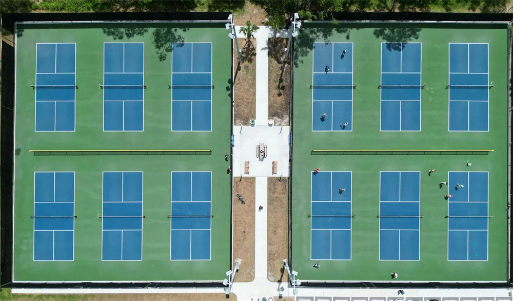 Aerial view of twelve blue and green pickleball courts with players on court